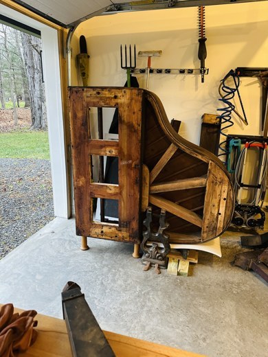 A grand piano stripped to its frame, being rebuilt as a bookshelf